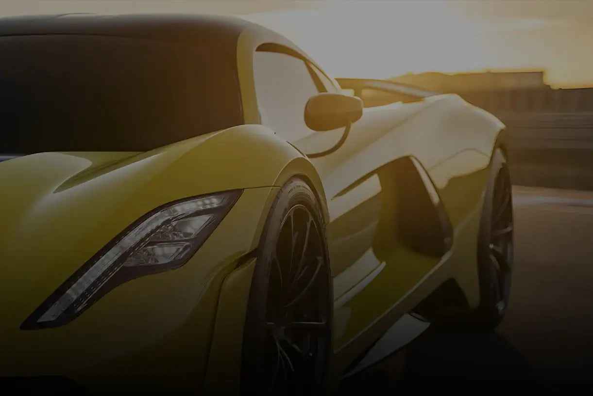 Yellow sports car with sleek design and black rims, captured at sunset on a racetrack